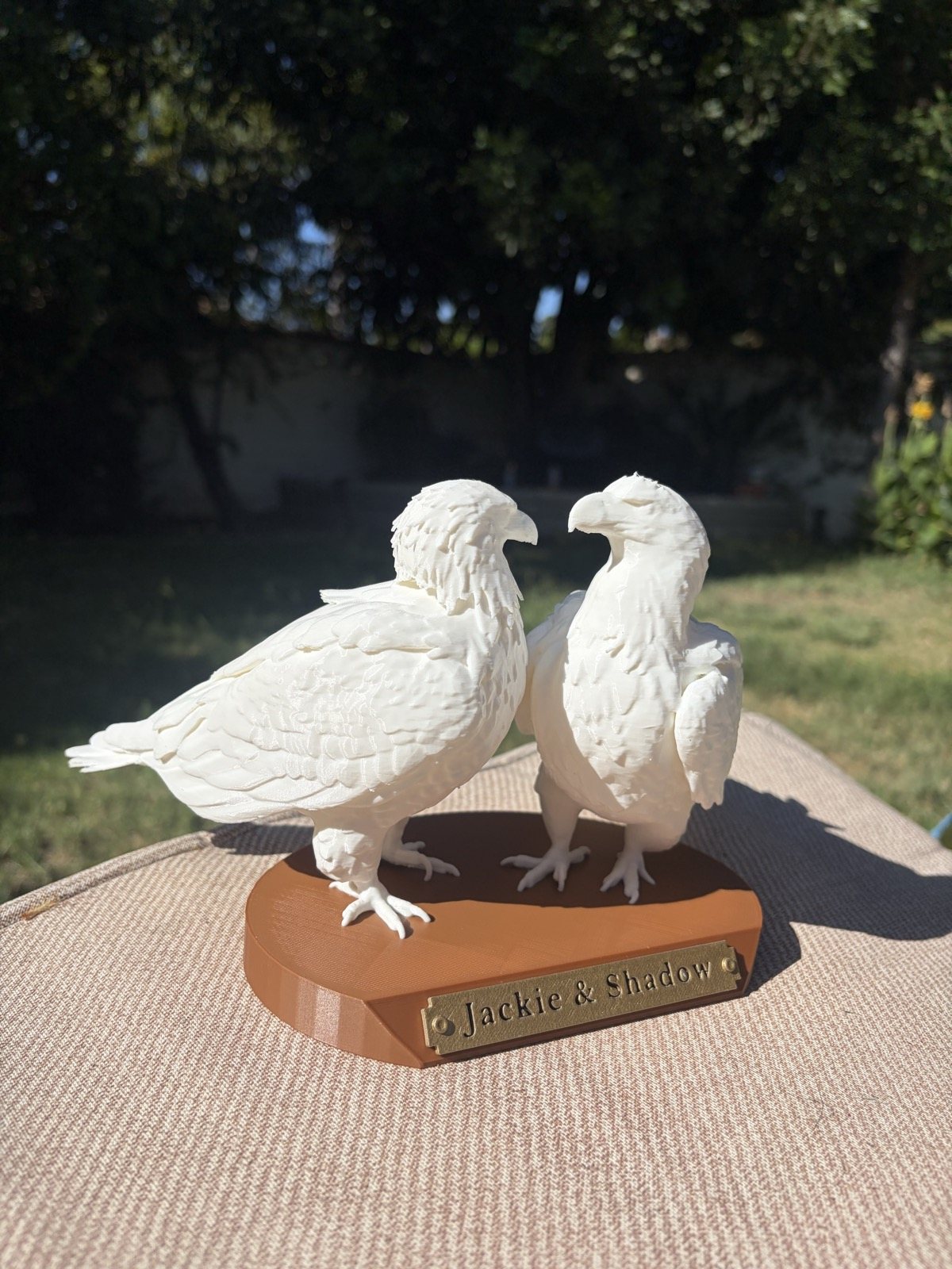 Jackie and Shadow sculpted in white, side by side on a warm wood-tone base with a gold name plate