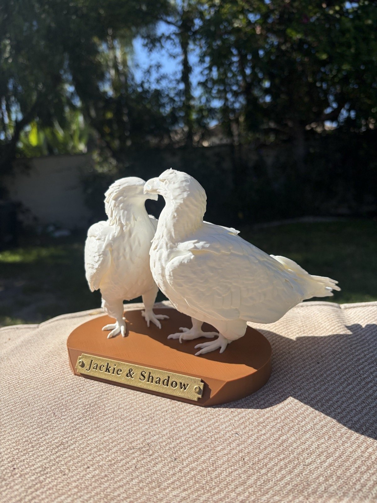 The white Jackie & Shadow statue from the side, showing the feather detail